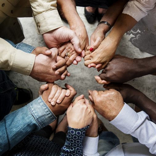 group-diverse-hands-holding-each-other-support-together-teamwork-aerial-view-copy-2706x1960-1-700x507-circle